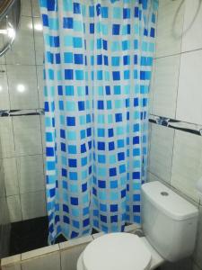 a bathroom with a toilet and a blue shower curtain at SHERANPAZ in Oxapampa