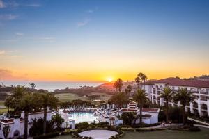 zachód słońca nad ośrodkiem z basenem i palmami w obiekcie Waldorf Astoria Monarch Beach Resort & Club w mieście Dana Point