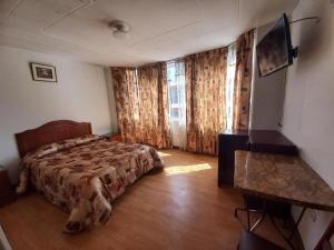 a bedroom with a bed and a desk in it at HOSTAL SUMITA HOUSE_INN in Puno