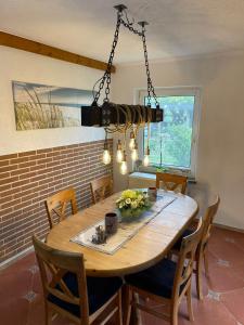 une table à manger avec des chaises et un lustre dans l'établissement Fewo am Saalerbodden, à Bartelshagen