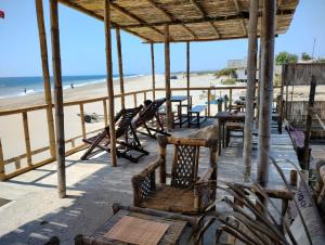 a deck with chairs and tables on the beach at Mancora Beach House in Máncora