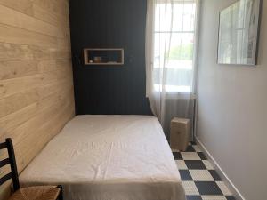 ein kleines Schlafzimmer mit einem weißen Bett und einem Fenster in der Unterkunft Maison de vacances Arzaël à 200m de la plage célèbre de Mr Hulot in Saint-Nazaire