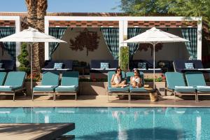 two women sitting on chairs next to a swimming pool at Waldorf Astoria Las Vegas in Las Vegas