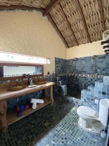 y baño con aseo, lavabo y espejo. en Hotel La Palma Del Paso Real- Solo adultos, en Santa Fe de Antioquia