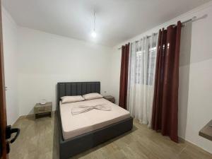 a bedroom with a bed and a window with curtains at Kleidi's home in Vlorë