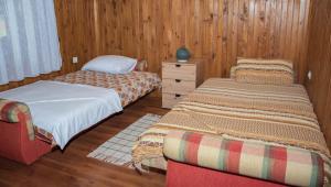 two beds in a room with wooden walls and wooden floors at Raj na selu - Padaberi paradise in Berane