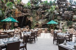 a restaurant with tables and chairs in front of a rock wall at Clarion Suites Guatemala City in Guatemala