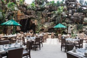 a restaurant with tables and chairs in front of a rock wall at Hotel Clarion Suites Guatemala in Guatemala