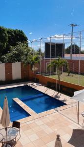 a pool with blue water and chairs and a fence at Apartamento em condomínio 24 hrs in Juazeiro do Norte