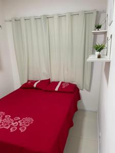 Una cama roja con sábanas rojas y flores rosas. en Apartamento em condomínio 24 hrs, en Juazeiro do Norte