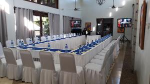 Villas de Palermo Hotel and Resort في سان خوان ديل سور: طاولة طويلة عليها كراسي بيضاء وزجاجات زرقاء