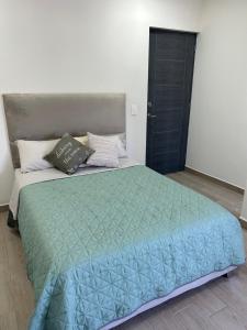 a bedroom with a large bed with a green comforter at Casa Nórdica - Monterrey in Monterrey