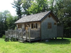 a small house with a deck in the grass at Rustic Lakefront Cottage Derby Paddles Lodge in Derby Center