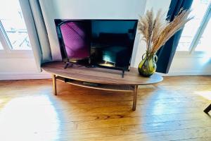 a tv sitting on a table with a vase on it at Nice apartment with wifi near town center and Wine Museum in Bordeaux