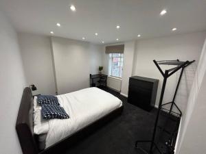 a bedroom with a bed and a dresser in it at Modern & Bright 4 Bedroom Home in Stoke on Trent