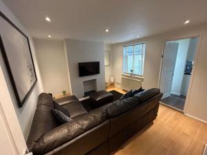 a living room with a brown leather couch and a television at Modern & Bright 4 Bedroom Home in Stoke on Trent