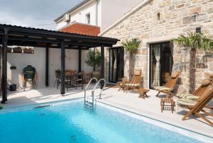 un patio con piscina y una casa en Blacksmith's House - rental house with heated pool en Posedarje