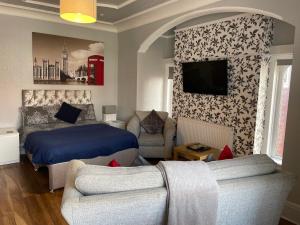 a bedroom with a bed and a couch and a tv at San Remo Apartments in Blackpool