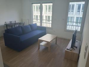 ein Wohnzimmer mit einem blauen Sofa und einem Tisch in der Unterkunft Magnifique T2 proche gare in Rueil-Malmaison