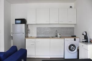 eine Küche mit weißen Schränken und einer Waschmaschine in der Unterkunft Magnifique T2 proche gare in Rueil-Malmaison