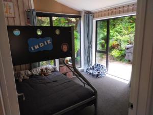 a bedroom with a bunk bed and a large window at Maitai Whare Iti - Adventure Cabins & House in Nelson