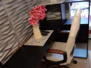 Un escritorio negro con un jarrón con flores. en APARTAMENTO PARA TRES PERSONAS a 10 minutos del centro de eventos valle del pacifico y a la misma distancia del centro de la ciudad Y también a 300 mts del Orquideorama en Cali