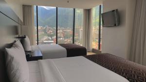 a hotel room with two beds and a flat screen tv at HOTEL CHACAO SUITES in Caracas