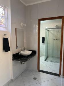 uma casa de banho com um lavatório e uma cabina de duche em vidro. em Hostel Passa4 em Passa Quatro