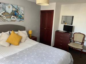 a bedroom with a bed and a desk with a television at San Remo Apartments in Blackpool