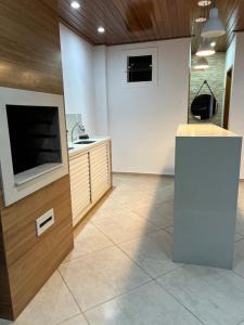 a kitchen with a sink and a tv in a room at Hostel Passa4 in Passa Quatro