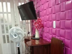 a room with a pink wall with a desk with a fan at APARTAMENTO PARA TRES PERSONAS a 10 minutos del centro de eventos valle del pacifico y a la misma distancia del centro de la ciudad Y también a 300 mts del Orquideorama in Cali