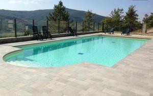 uma piscina com água azul e cadeiras em La Verna House em Chiusi della Verna