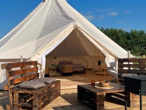 une tente en toile avec deux chaises et une table dans l'établissement Glamping Rusne, à Rusnė