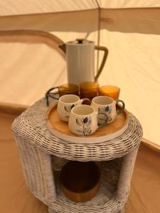 盧思內的住宿－Glamping Rusne，柳条桌,上面有杯子和搅拌器