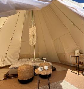 a bed in a tent with two chairs and a table at Glamping Rusne in Rusnė