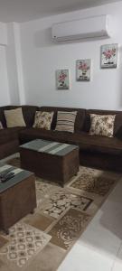 a living room with a brown couch and a table at حجز شاليهات مارينا دلتا ومارينا لاجونز in Al Ḩammād