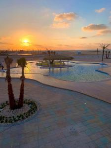 un complejo con palmeras y la playa al atardecer en حجز شاليهات مارينا دلتا ومارينا لاجونز en Al Ḩammād