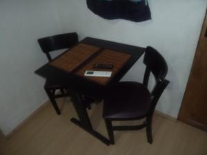een kleine tafel met twee stoelen en een afstandsbediening bij Angra Suítes em Família in Angra dos Reis