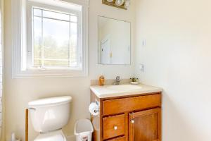 a bathroom with a toilet and a sink and a window at Maine Country Getaway in Holden