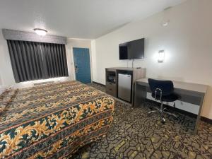 a hotel room with a bed and a desk and a television at Countryside Inn in Malakoff