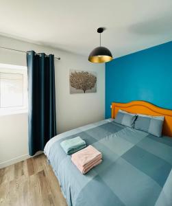 1 dormitorio con 1 cama grande y pared azul en maison chaleureuse ,avec piscine, spa, Futuroscope, en Jaunay-Clan
