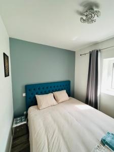 1 dormitorio con 1 cama grande y cabecero azul en maison chaleureuse ,avec piscine, spa, Futuroscope, en Jaunay-Clan