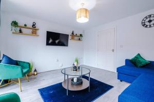 Luxury Large Leeds 10bed 2.5bath Modern House Free Parking في Robin Hood: غرفة معيشة مع أريكة زرقاء وطاولة