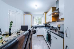 a kitchen with white cabinets and a table in it at Luxury Large Leeds 10bed 2.5bath Modern House Free Parking in Robin Hood