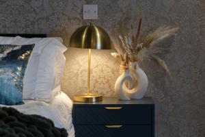 una cama con una lámpara y un jarrón en una mesita de noche en Opulence Studio in Sheffield, en Sheffield