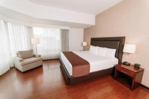 Hotel Clarion Suites Guatemala في غواتيمالا: غرفه فندقيه بسرير وكرسي