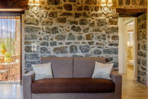 un sofá en una habitación con una pared de piedra en Casale Buona TerraMia, en Castiglione di Sicilia