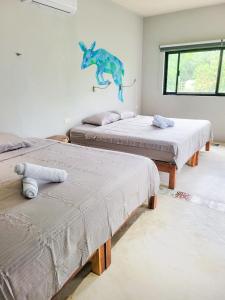 three beds in a room with a dinosaur on the wall at Maui Hostels Tulum in Tulum