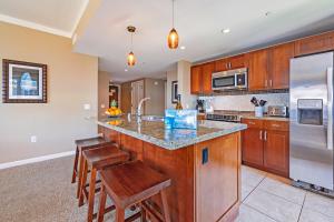 a kitchen with wooden cabinets and a island with bar stools at HK #539 in Lahaina
