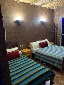 1 dormitorio con 2 camas y luces en la pared en Gite D'Etape Amced, en Goulmima